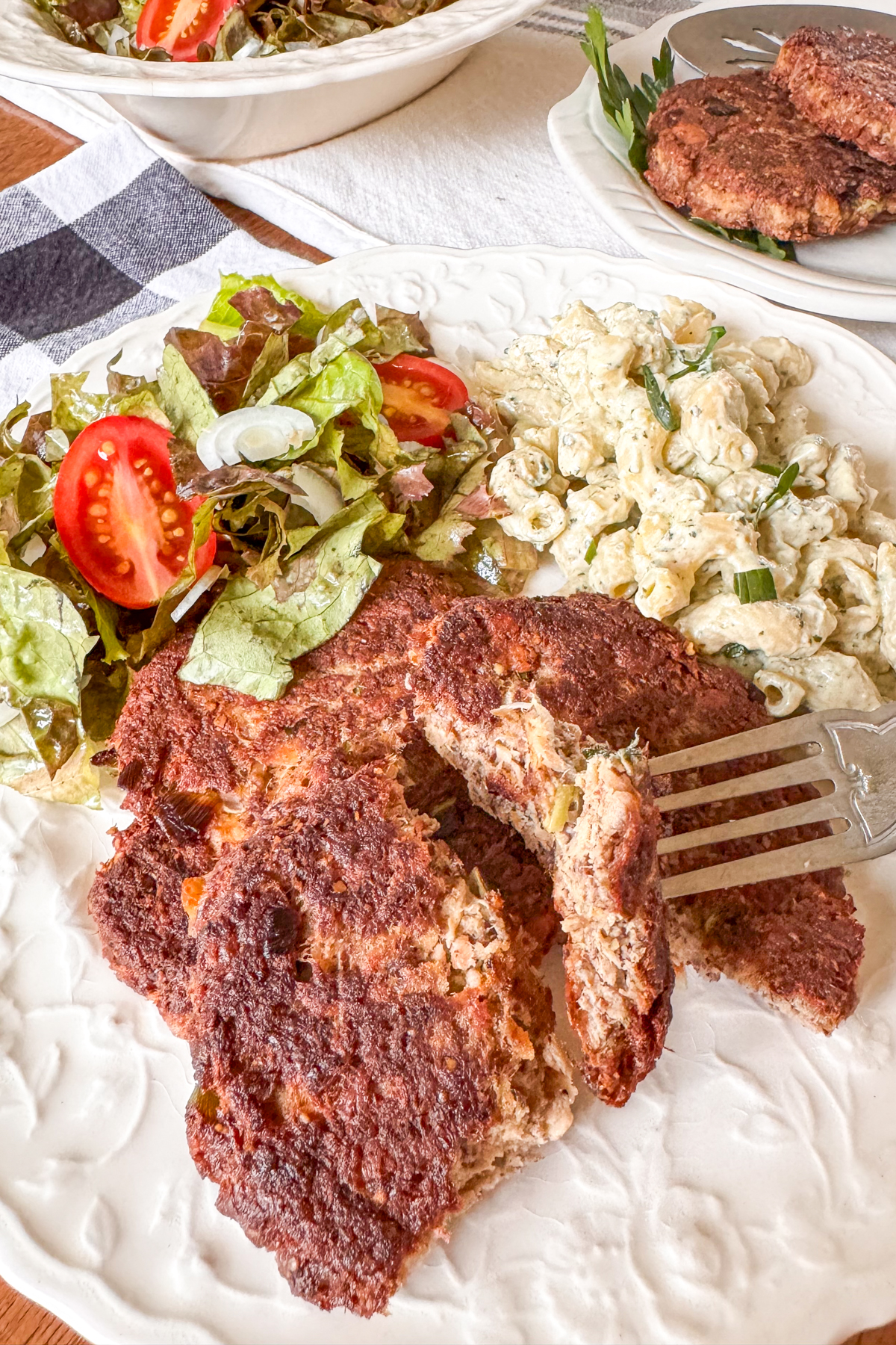 Cutting into salmon patties on white plate