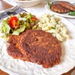 salmon patties on a plate with salad and pasta