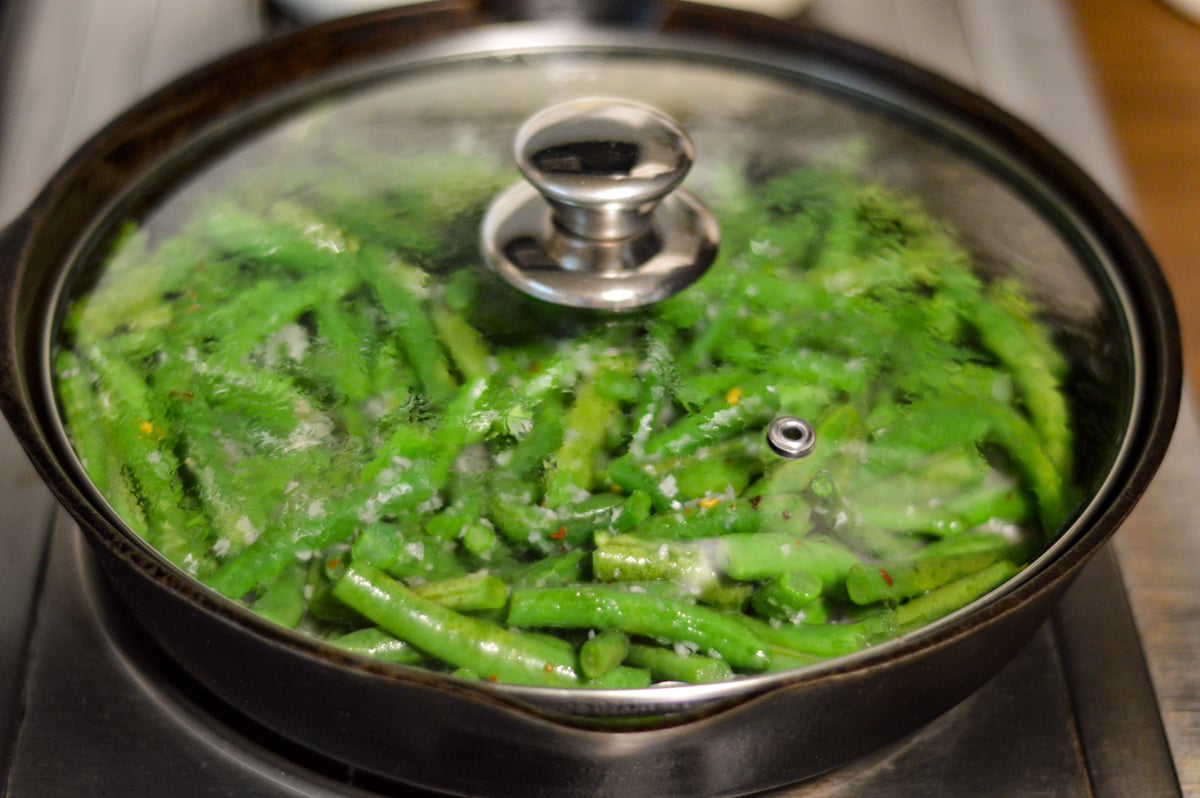 cooking green beans in a skillet with lid