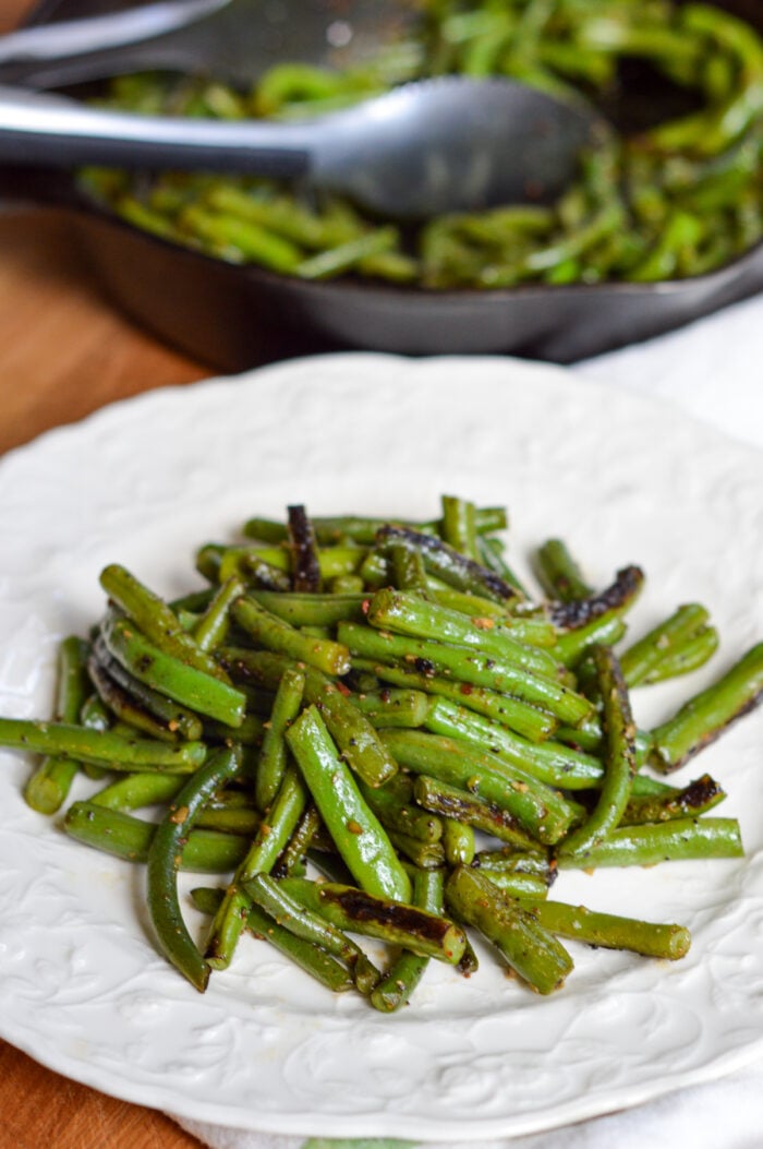 garlic green beans on white plate with skillet