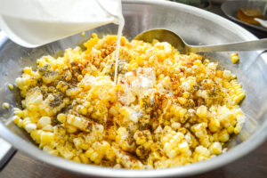 adding cream to bowl of baked corn ingredients
