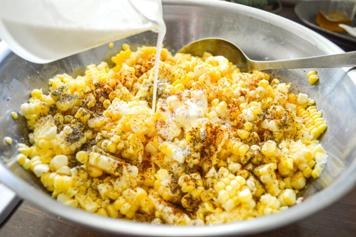 adding cream to bowl of baked corn ingredients
