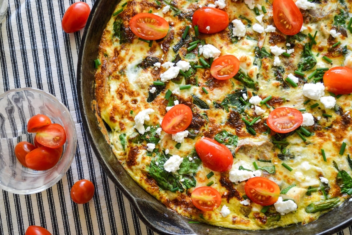 chicken spinach frittata in cast iron pan with tomatoes