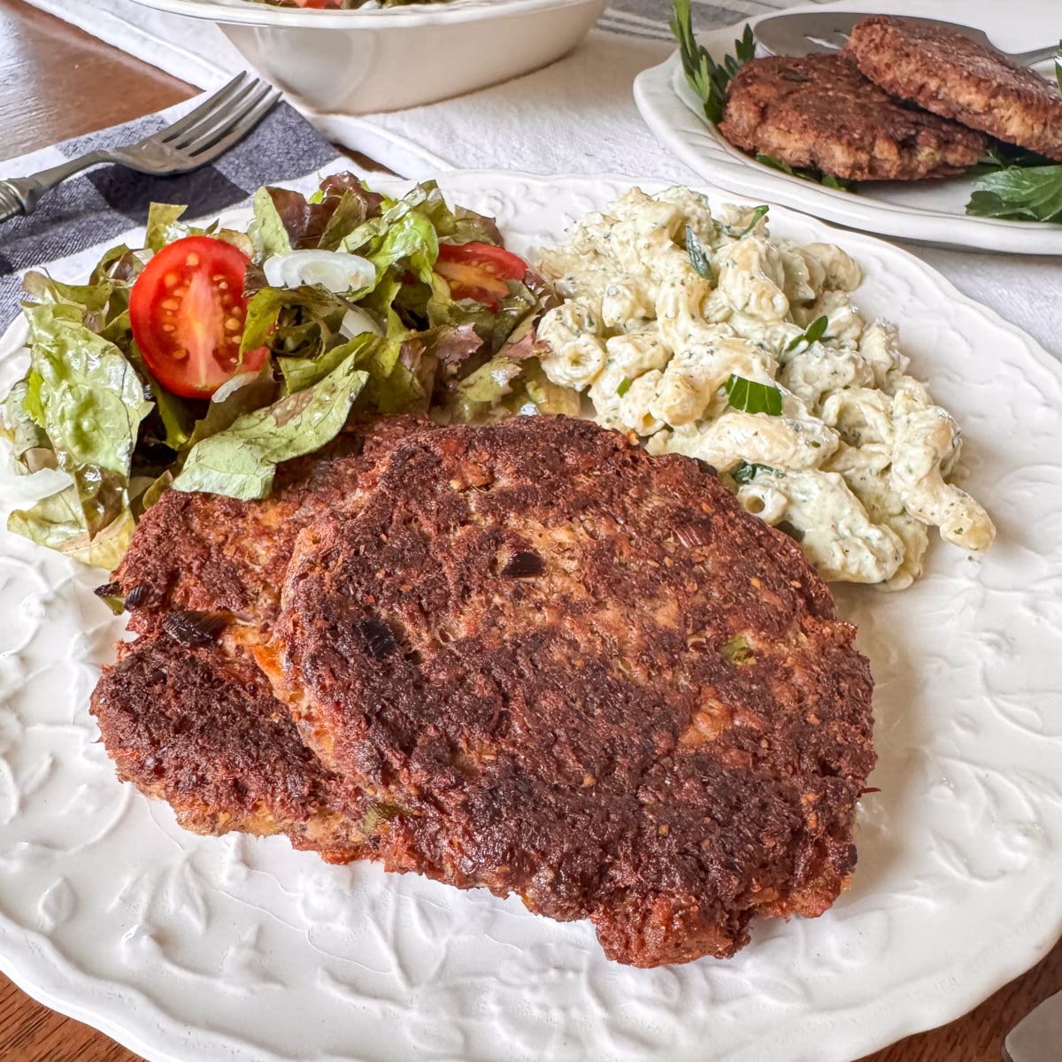 salmon patties on plate with salad and pasta