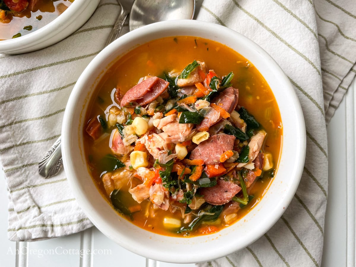 cajun chicken vegetable soup in white bowl with striped napkins
