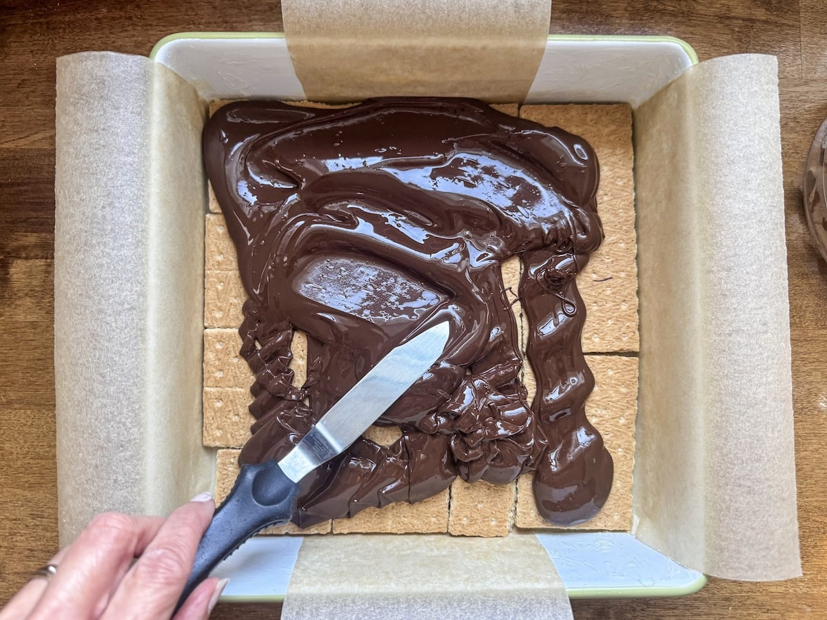 spreading melted chocolate over graham crackers