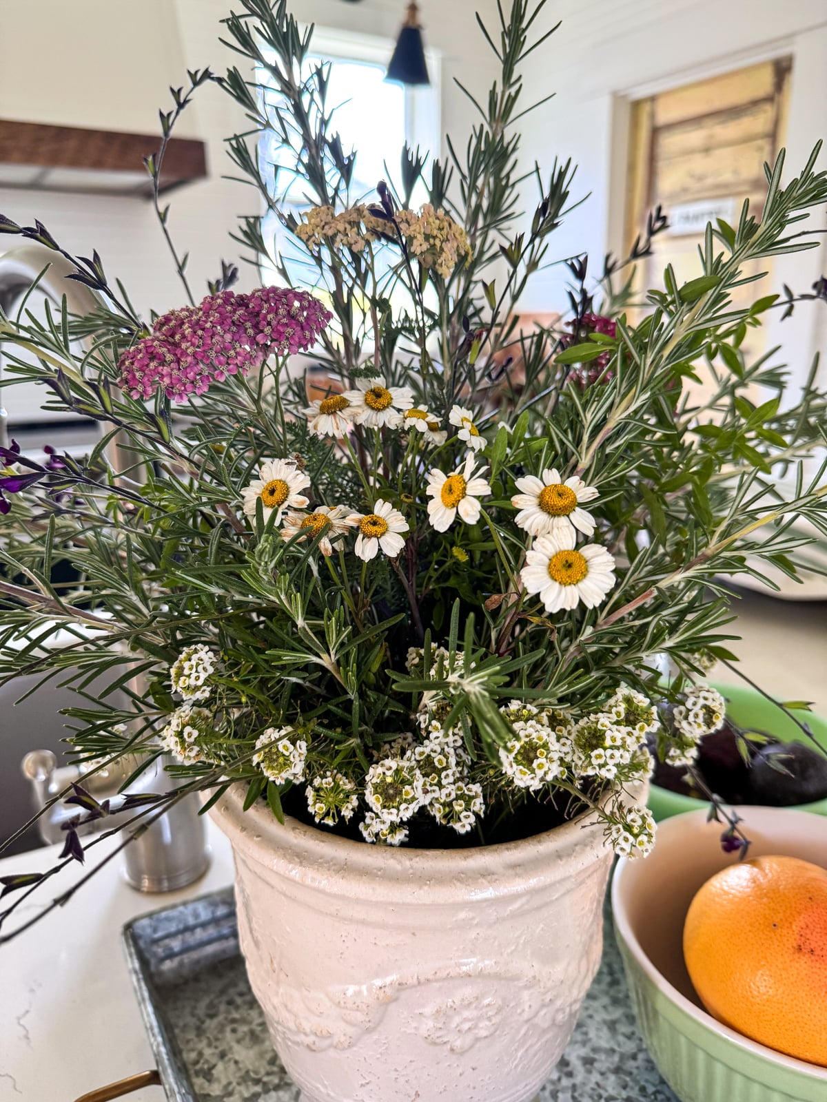 rosemary and a few flowers in white vase