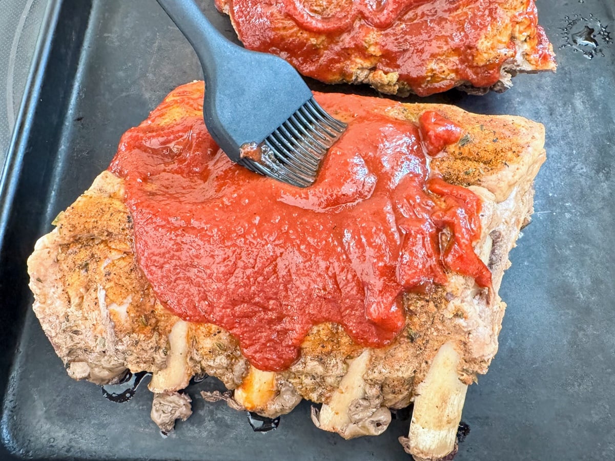 brushing bbq sauce on ribs
