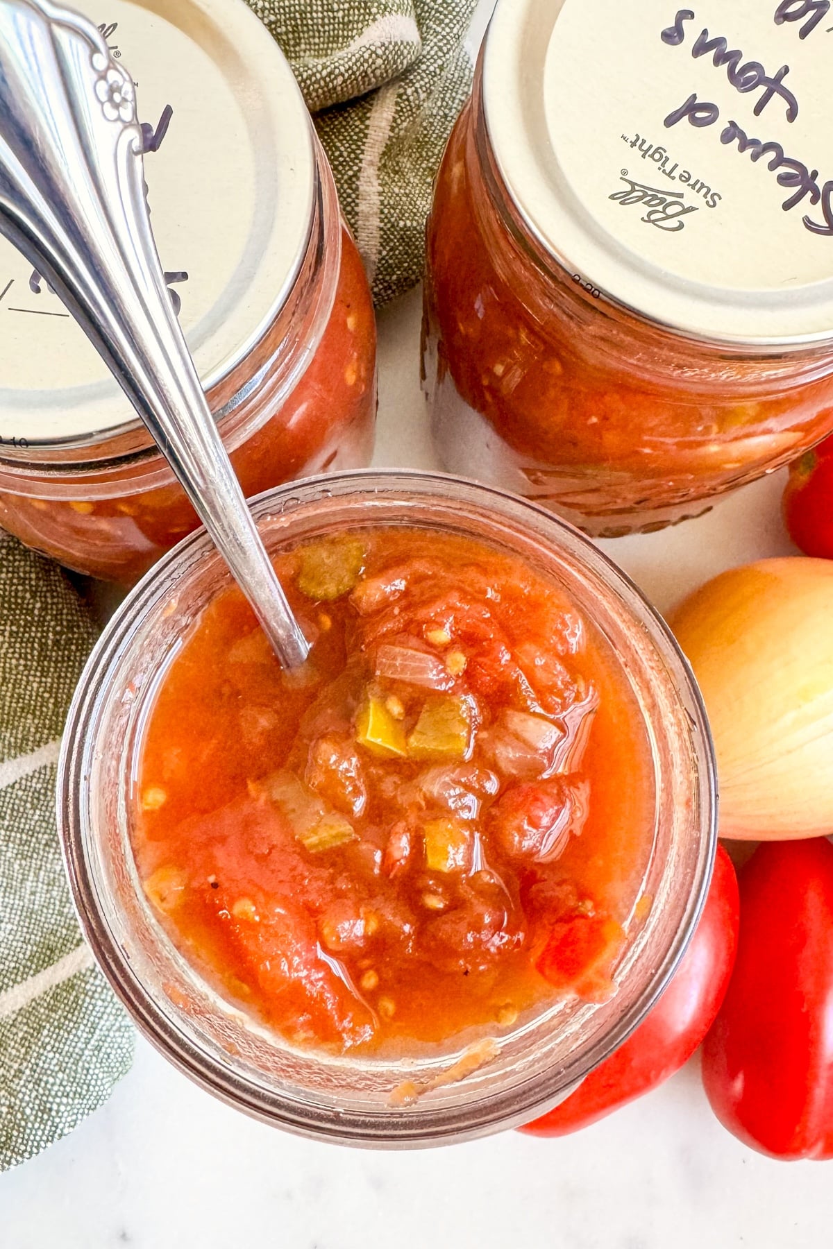 open jar of stewed tomatoes with spoon
