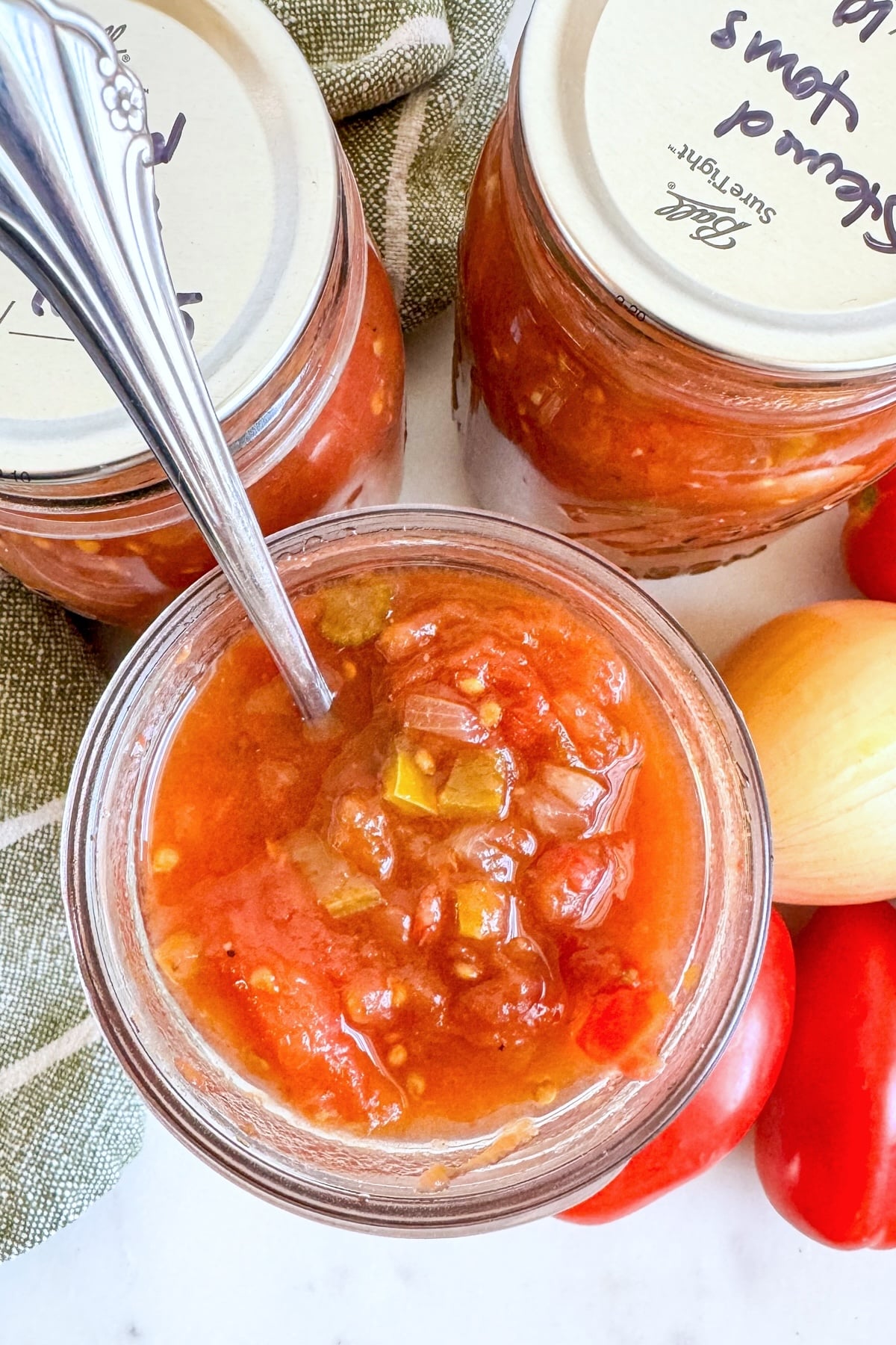 open jar of stewed tomatoes with spoon