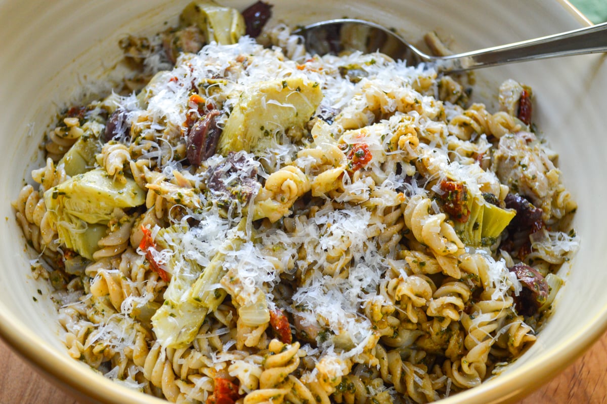 serving bowl of mediterranean chicken pesto pasta with spoon