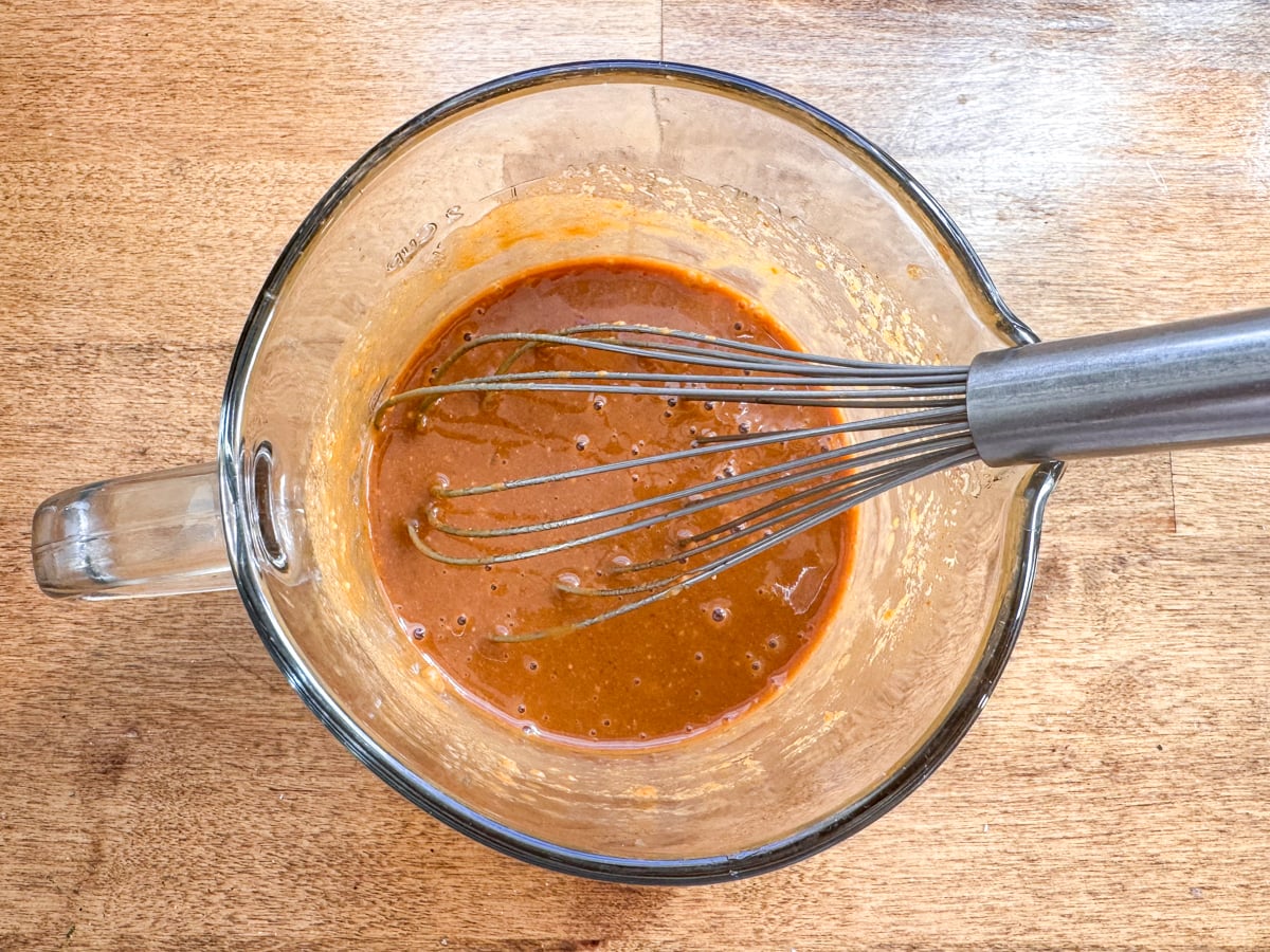 whisking peanut sauce in glass cup