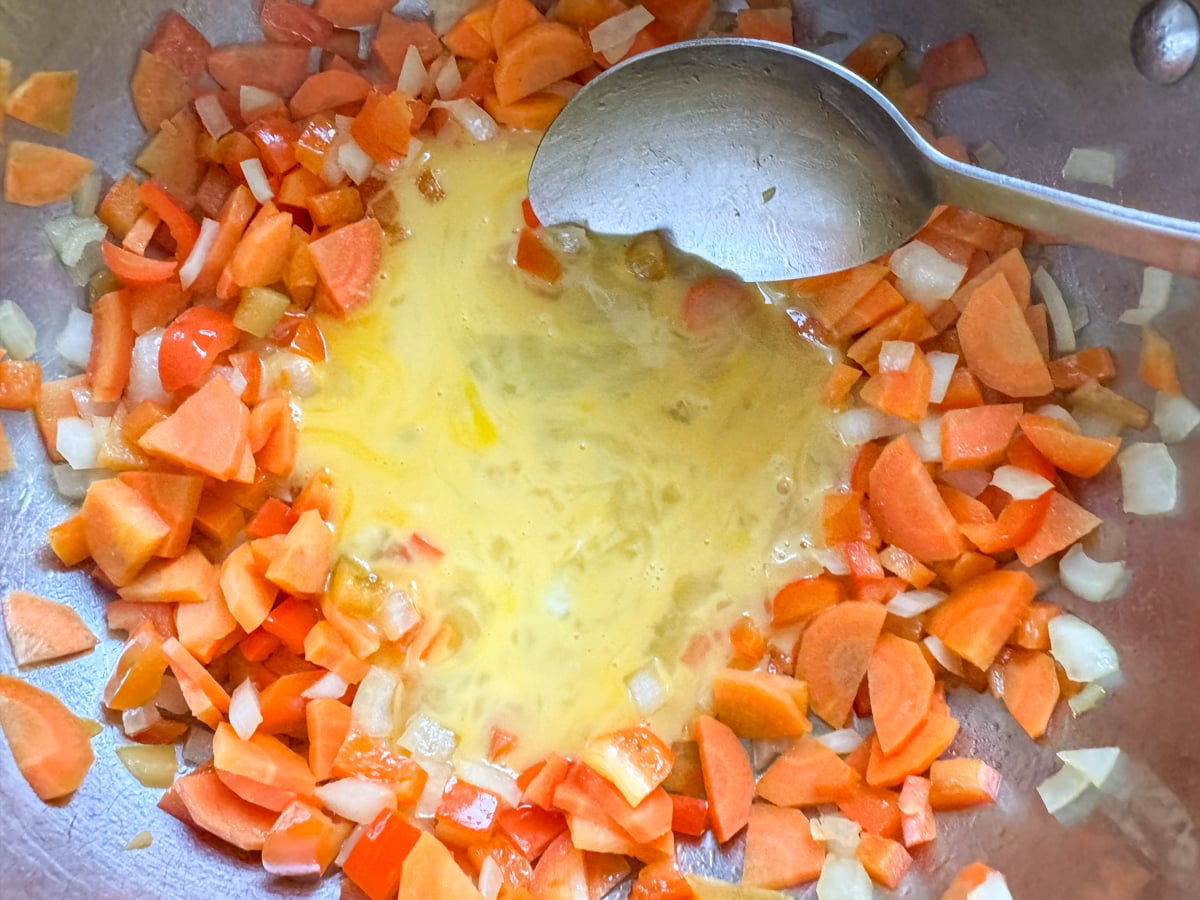 scrambling eggs in skillet with vegetables